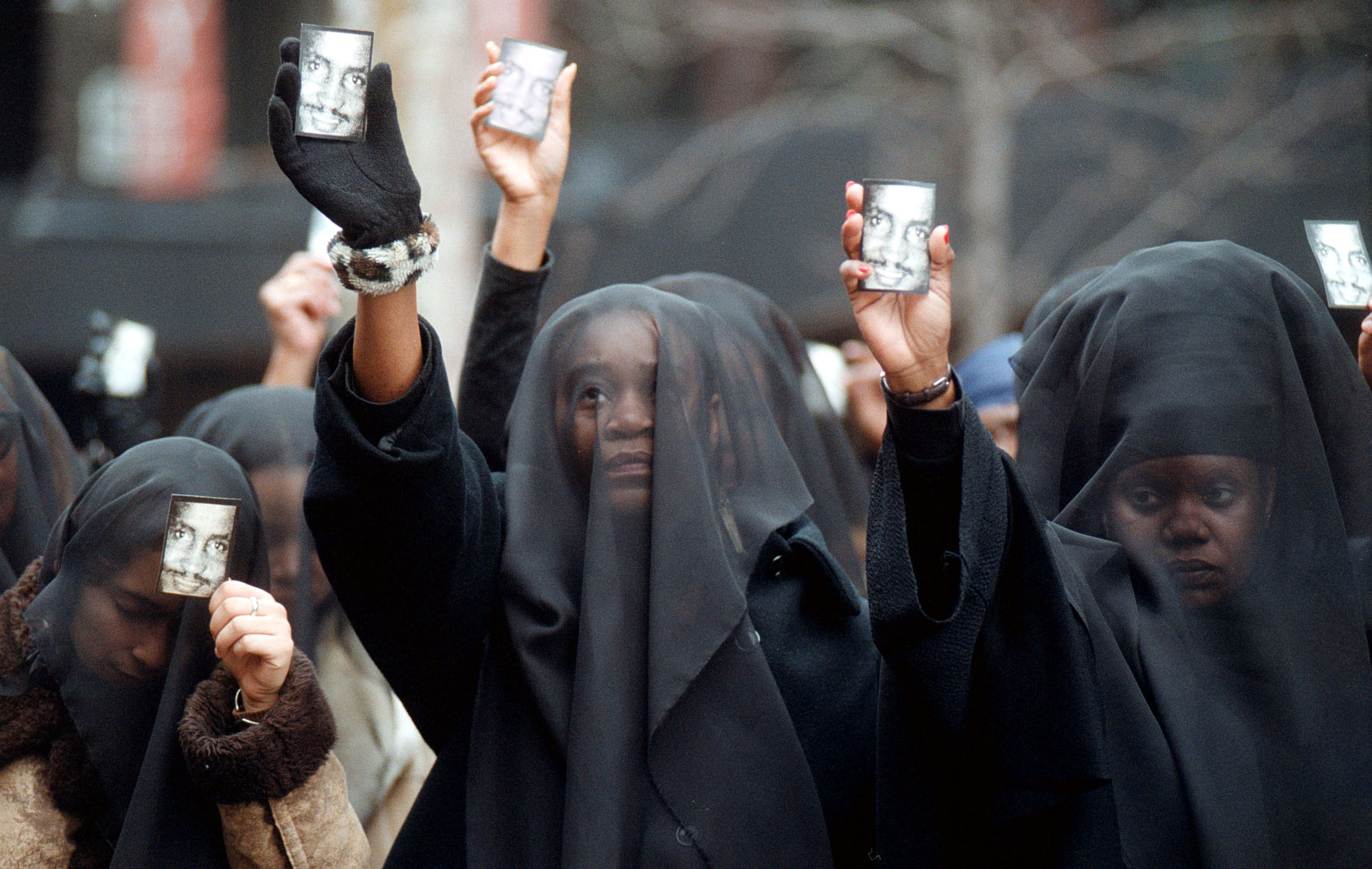 Women wearing veils of mourning hold cards with the image of Amadou Diallo before the start of a prayer vigil outside the United Nations February 27, 2000 in New York. The Rev. Al Sharpton is holding the vigil to protest the acquittal of four white New York City police officers charged in the February 1999 shooting death of Diallo. (Photo by Spencer Platt/Getty Images)