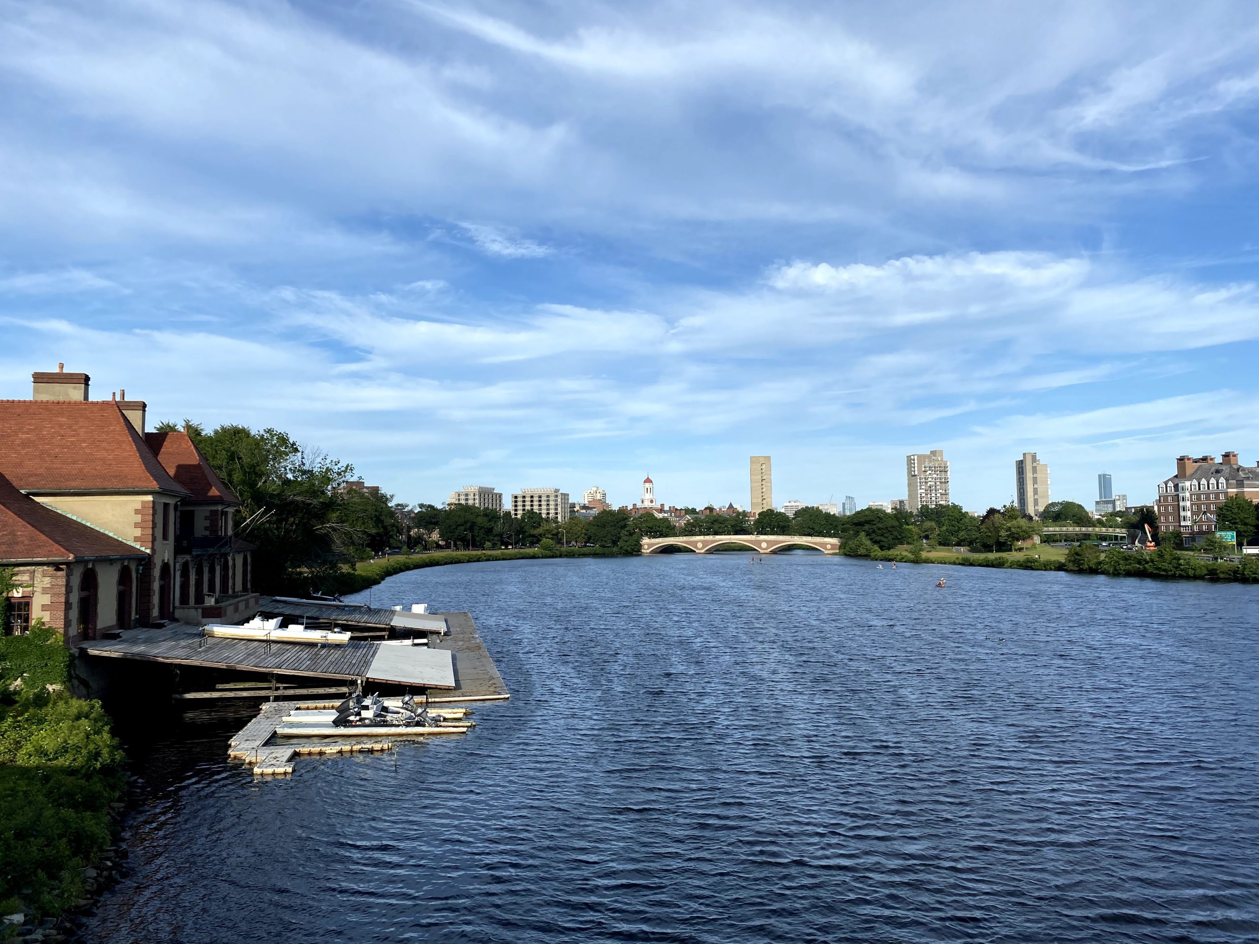 
            The Charles River flows and skyscrapers rise in the distance.